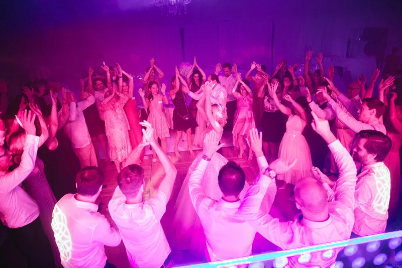 A full dance floor with raised hands and evening lighting.