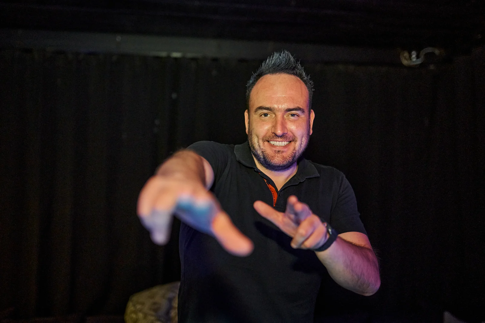 Tomy Vertigo with outstretched hands in front of the DJ booth.