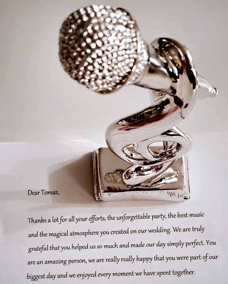 A silver microphone-shaped award resting on a printed wedding thank-you letter.