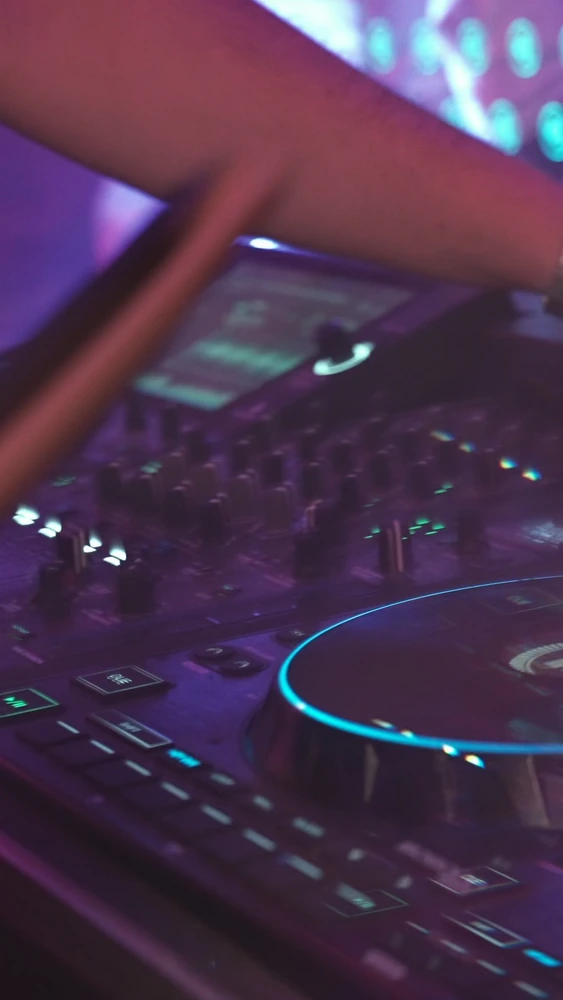 Video cover: a close-up of a hand working a DJ controller illuminated in cyan and purple.