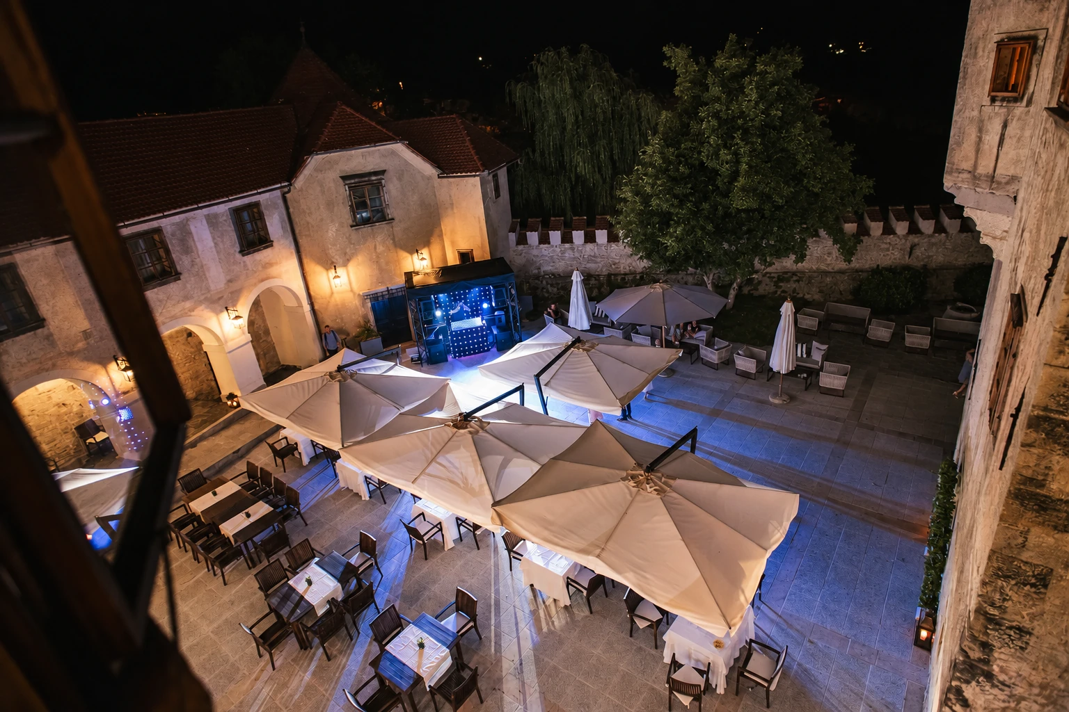 An evening setup in a stone courtyard with a music stage.