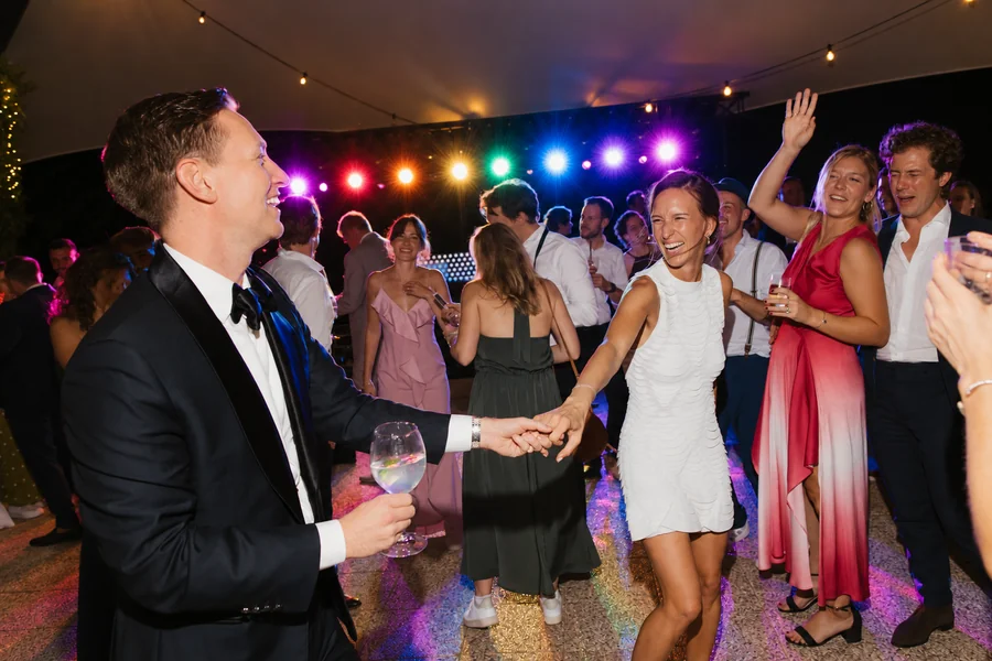 Wedding guests dancing under evening lights.