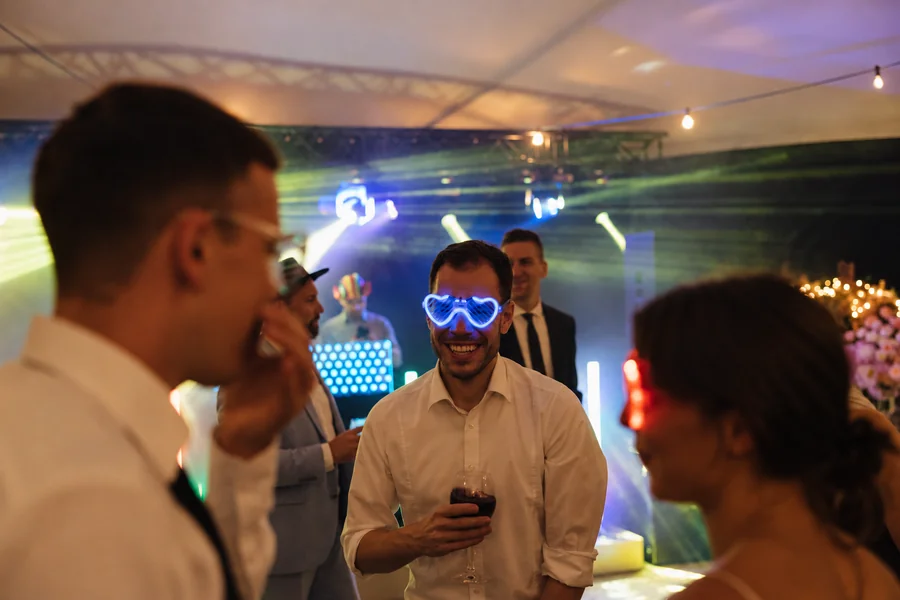 Wedding guests celebrating under coloured lighting.