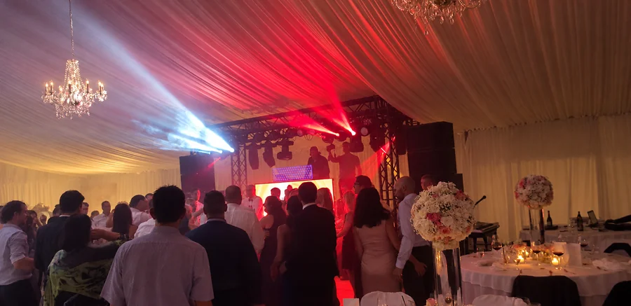 Guests at an evening celebration with stage lighting.
