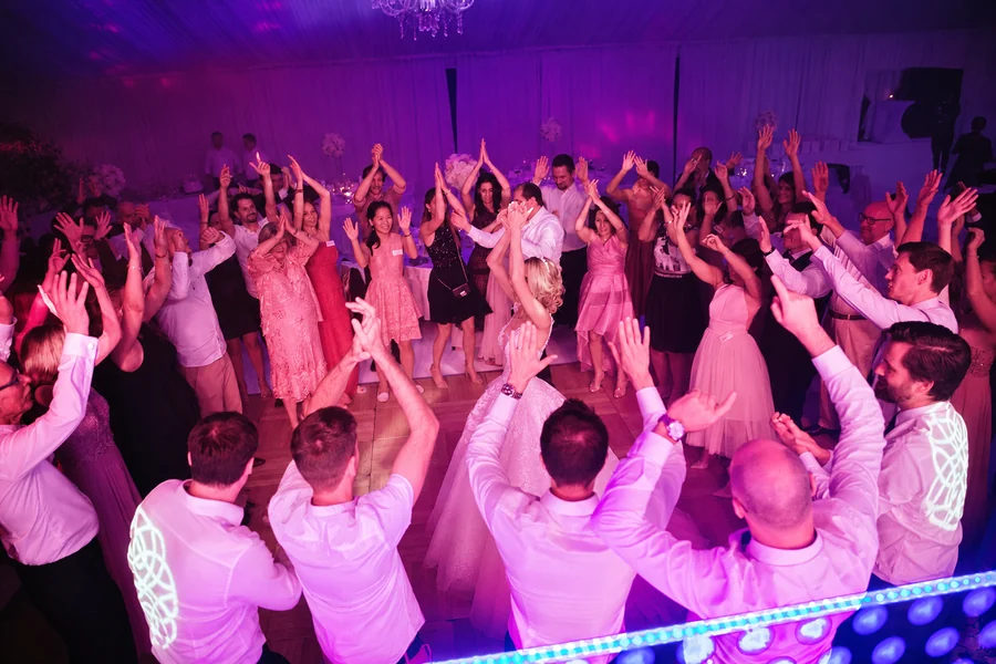A full dance floor with raised hands and evening lighting.