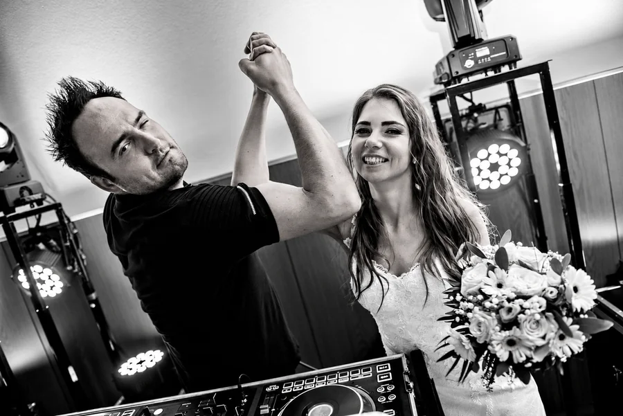 Tomy Vertigo and a bride beside the DJ booth, captured in black and white.