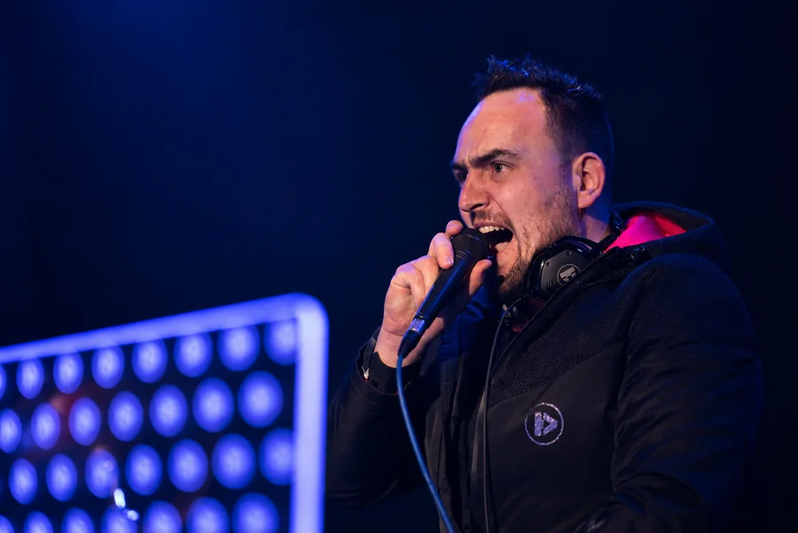 Tomy Vertigo with a microphone and headphones during a performance.