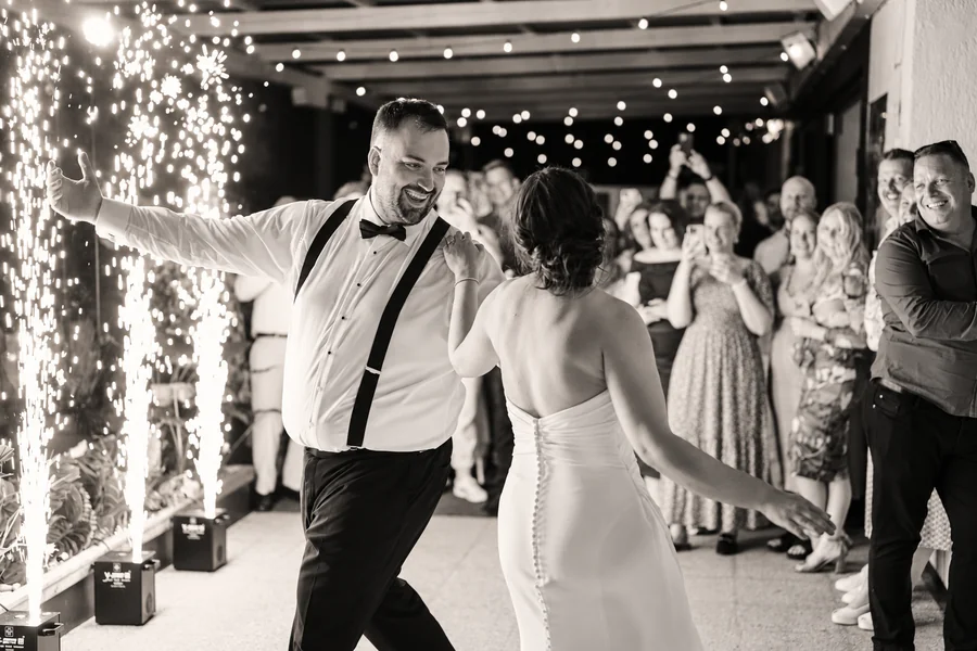 A wedding couple and guests on the dance floor, captured in black and white.